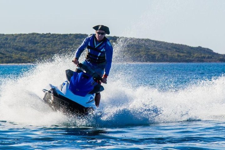 a man riding on the back of a boat in a body of water