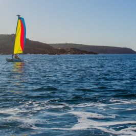 A man on his jet ski looking at a nearby sailboat