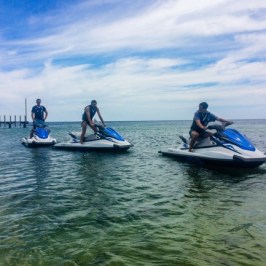 Three men standing on their jet skis