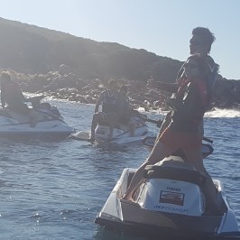 Two guests turning around on their jet ski to give the camera the thumbs up